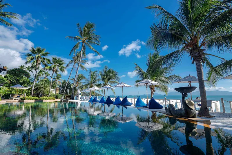Beachfront infinity pool with palms, parasols and bean bags facing the sea at Anantara Bophut Koh Samui