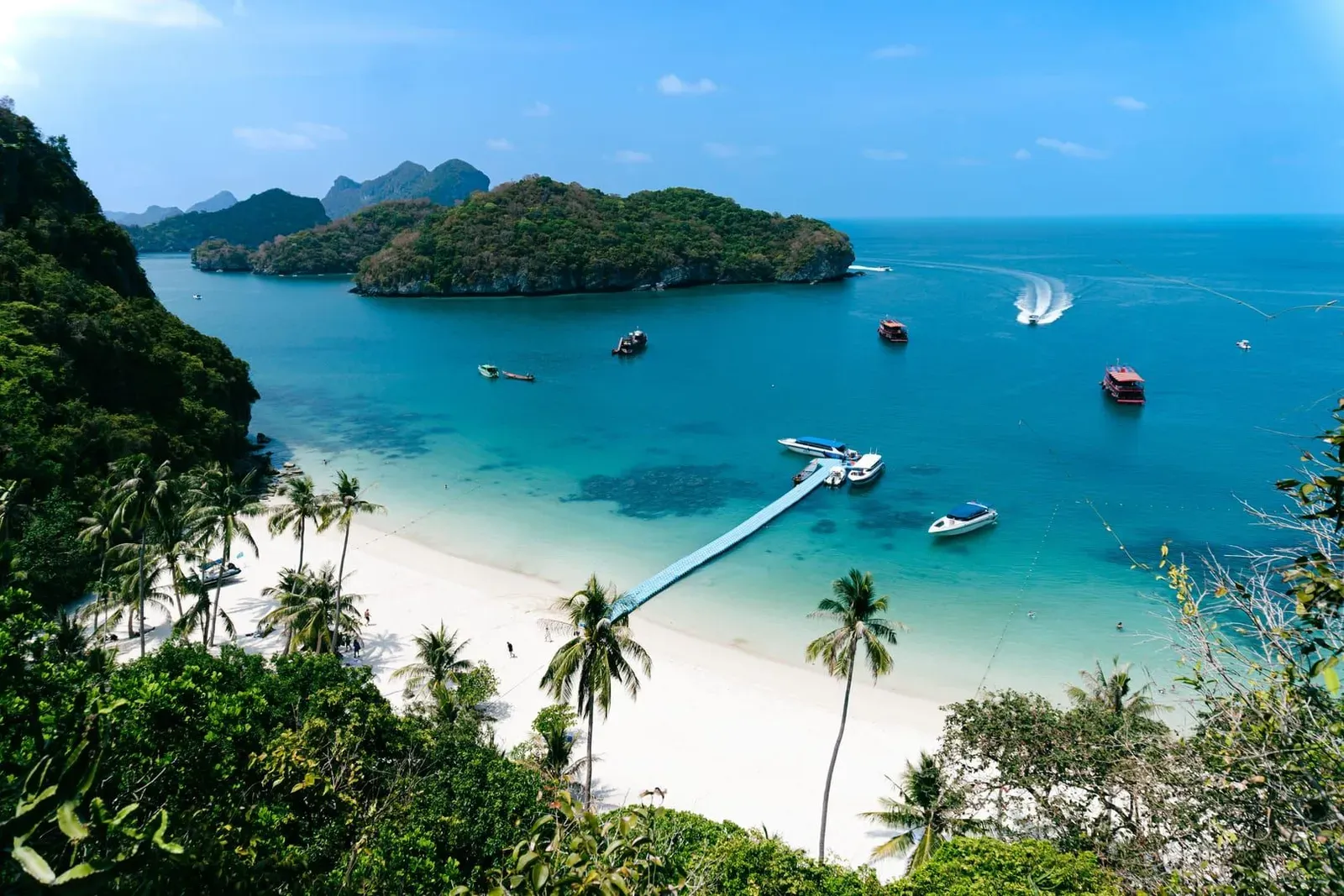 Tour boats moored off a white-sand beach beneath the park's limestone islands