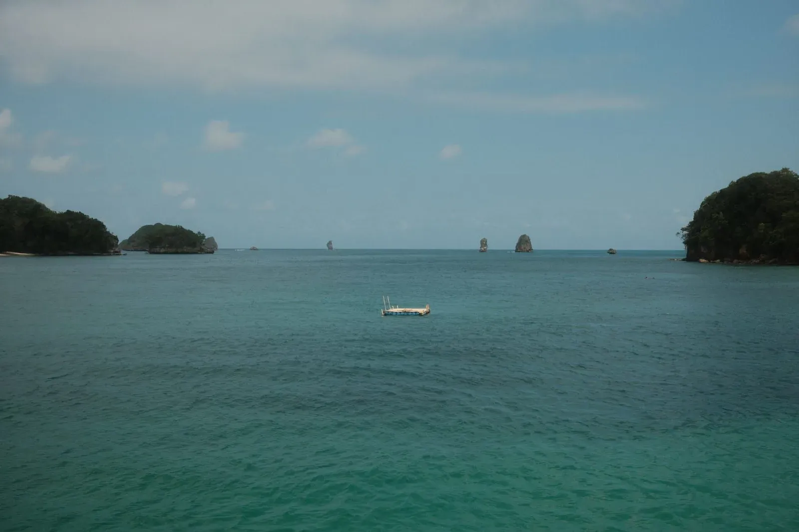 Rock stacks rising from calm water between two forested islands