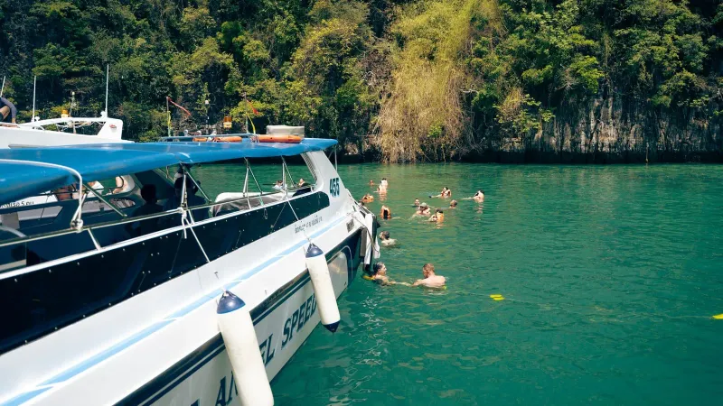 Tourists swimming in turquoise water near a speedboat on a Pig Island and Koh Tan day trip