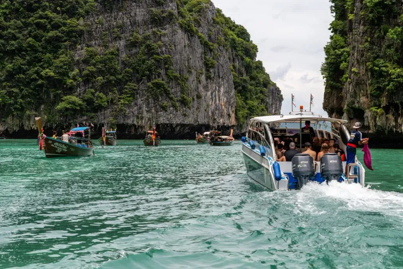 Speedboat cruising past dramatic limestone island cliffs on a private Gulf of Thailand charter