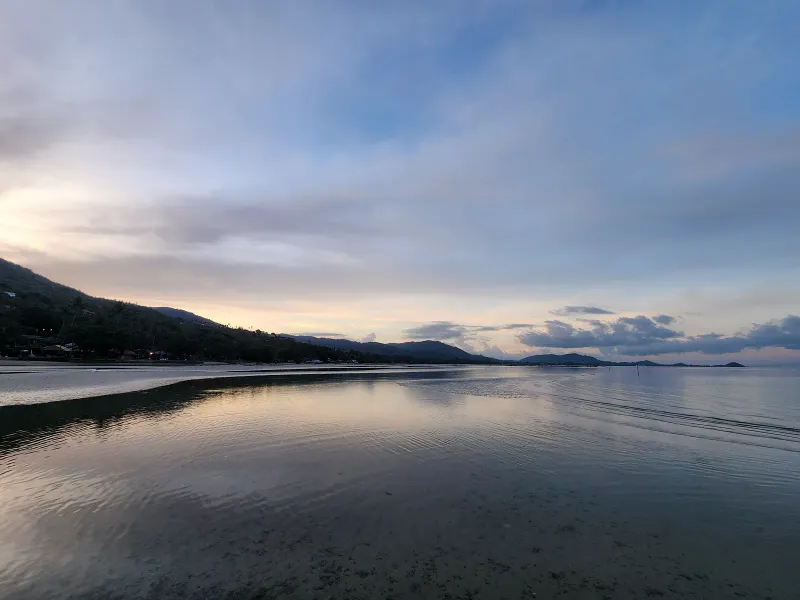 Calm low-tide water reflecting the dusk sky along Bang Makham's shoreline