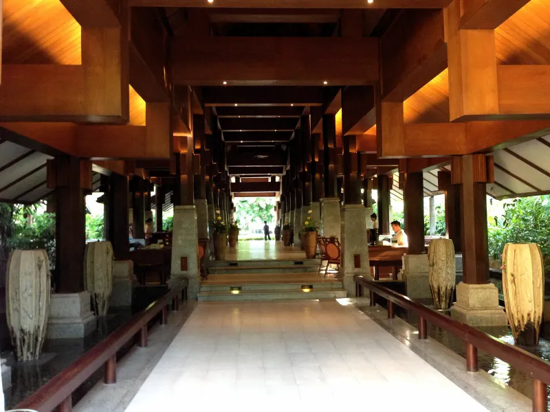 Covered teak walkway through the Bo Phut Resort and Spa lobby with carved Thai wood beams
