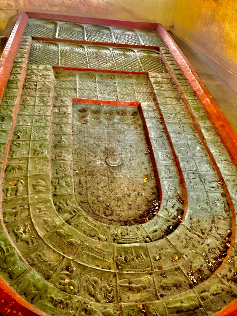 Close-up of the carved stone footprint slab with concentric ring patterns at the shrine