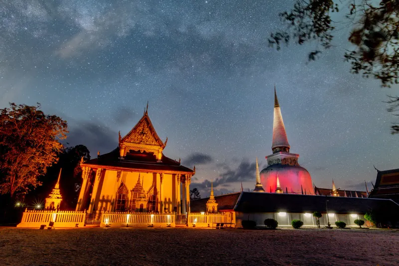 A temple and its chedi lit up under the stars