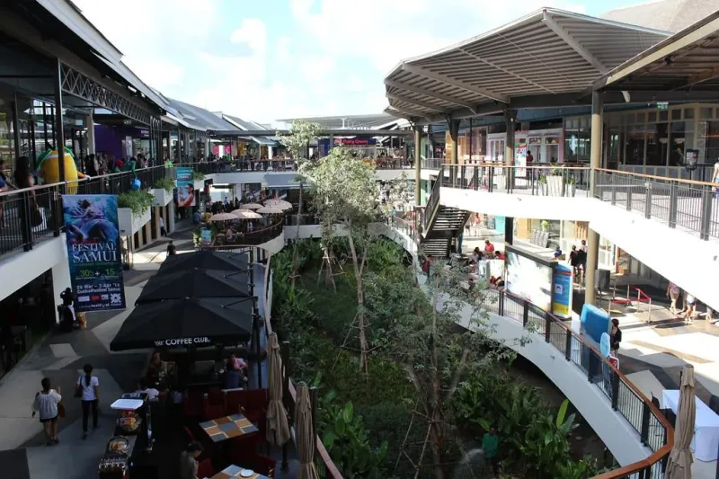 Central Samui shopping mall interior courtyard with escalators, terrace dining and landscaped greenery