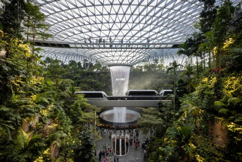 Large airport atrium with trees and shops, typical of a long-haul connection hub