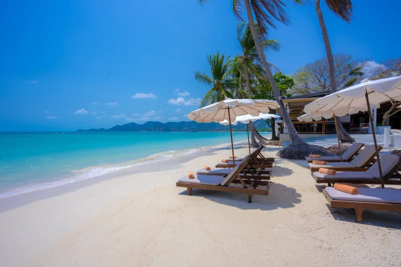 Sunbeds and umbrellas on white sand at a Chaweng beach resort on Koh Samui