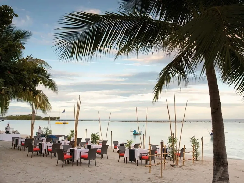 Dinner tables set on the sand at sunset with torches and palm trees, Chaweng Regent Beach Resort