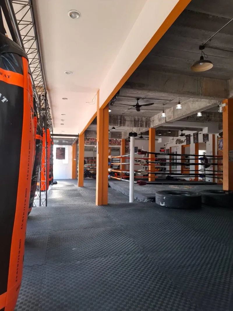 Bo Phut gym interior with a boxing ring and heavy bags beside an orange post