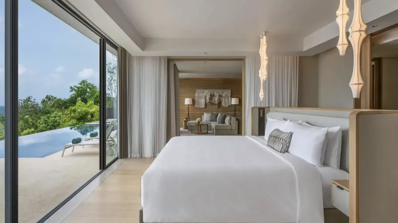 Villa bedroom with floor-to-ceiling glass opening to a private infinity pool at Conrad Koh Samui