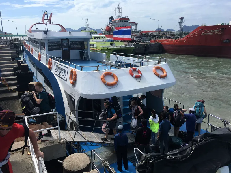 Backpackers with rucksacks boarding a passenger ferry at a mainland pier on the Gulf of Thailand