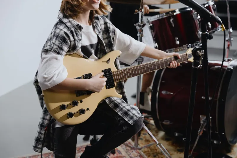 Young musician playing an electric guitar, the kind of school-age player who rehearses at a community music room