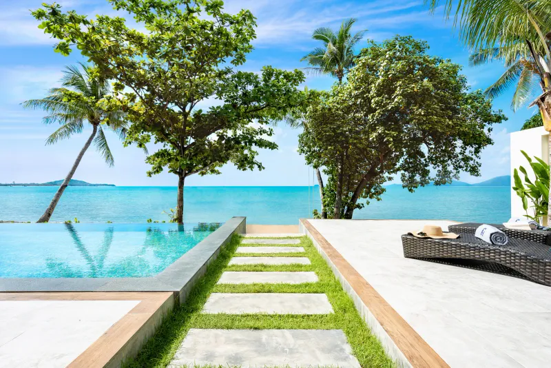 Villa infinity pool and stone stepping path leading to the sea at Fair House Villas & Spa