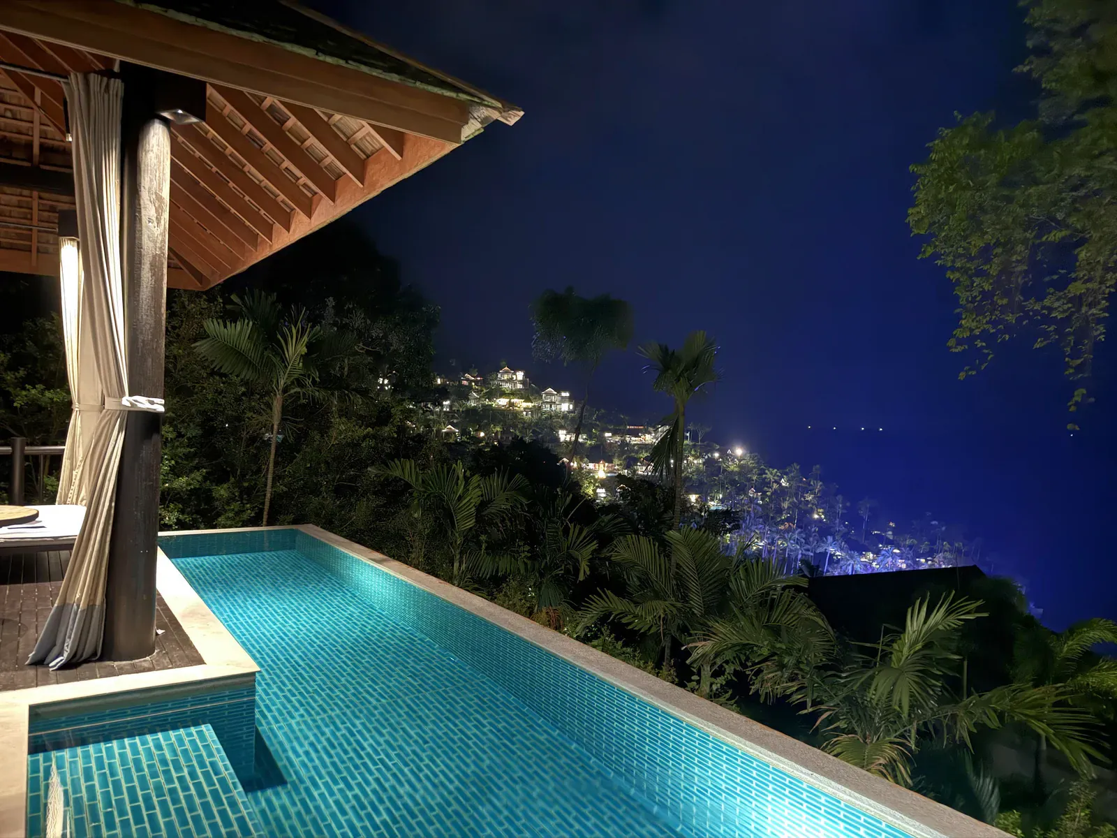 A Four Seasons Koh Samui pool villa at night, the bay lights below