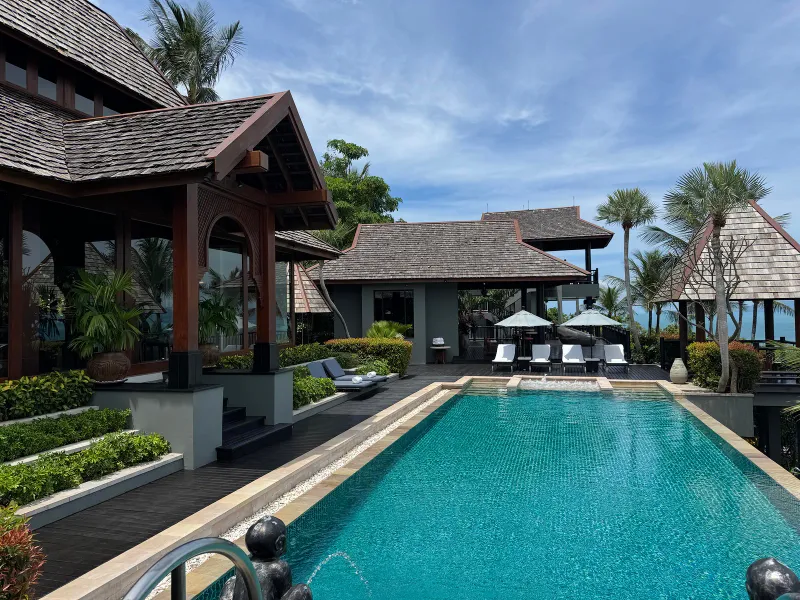 Long infinity pool with Thai-style timber roofs and sun loungers at Four Seasons Resort Koh Samui