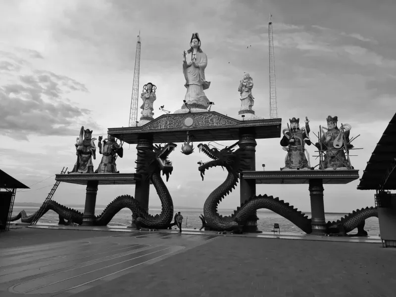 Black and white photo of Guan Yin statue surrounded by dragon sculptures in Surabaya, Indonesia