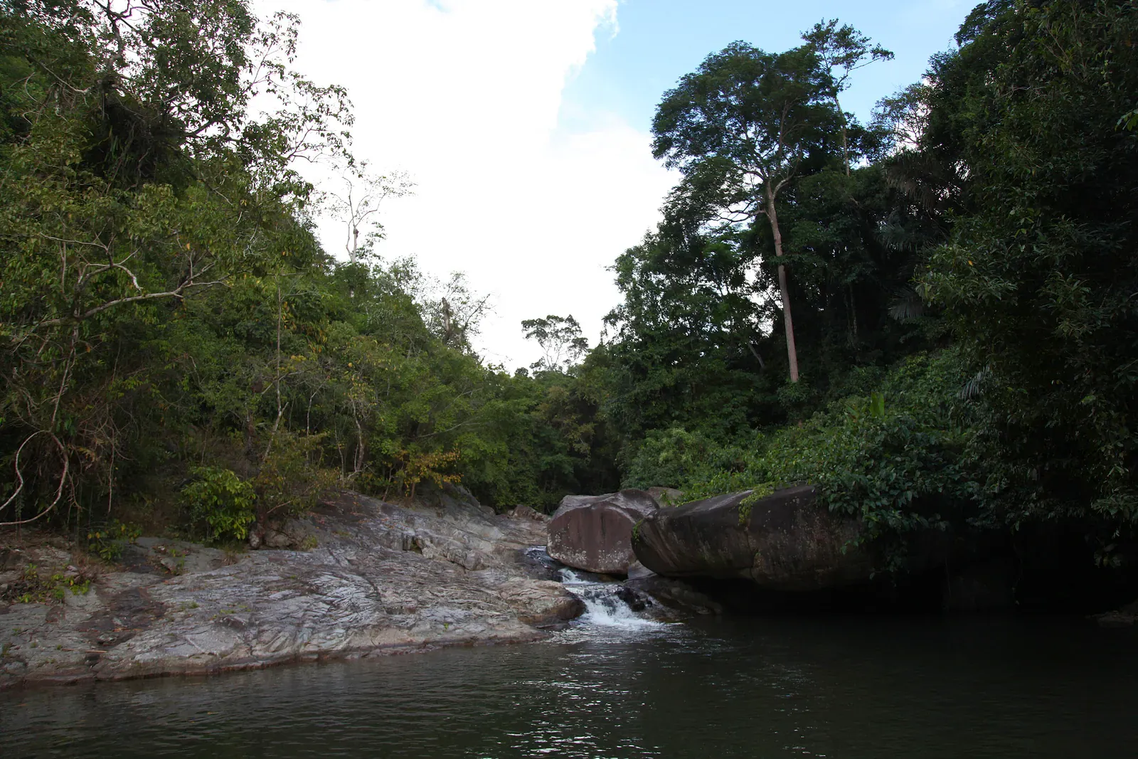 Hin Lad Waterfall's main cascade dropping over granite boulders into a swimming pool
