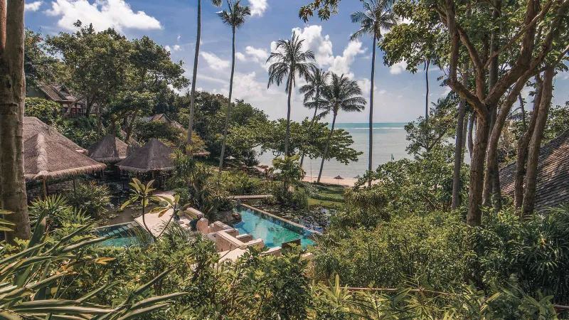 Aerial view of the resort's tiled pool set among gardens and thatched roofs