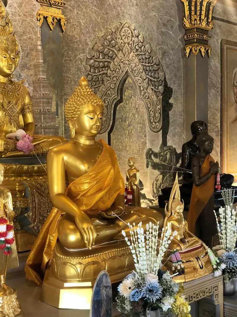 Golden Buddha statue seated among smaller gilded figures inside a temple hall