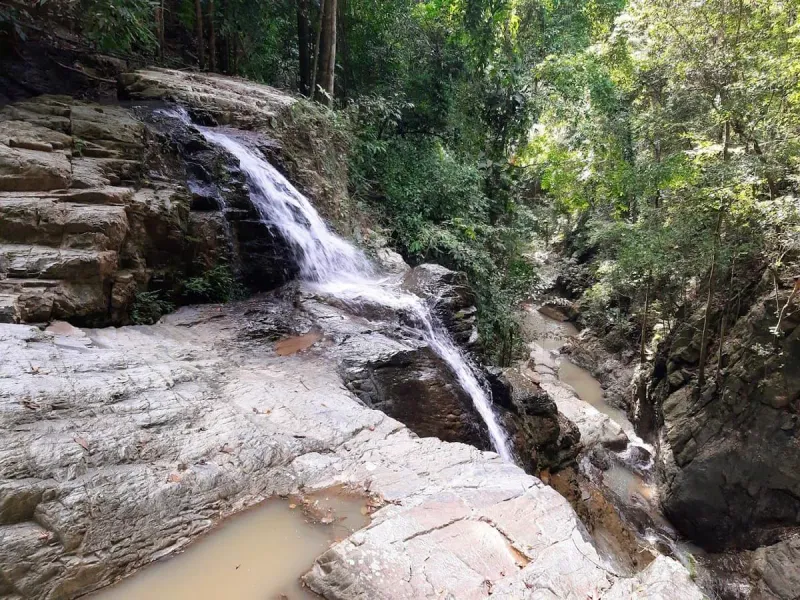 A tiered cascade at Khun Si Waterfall flowing over granite rock