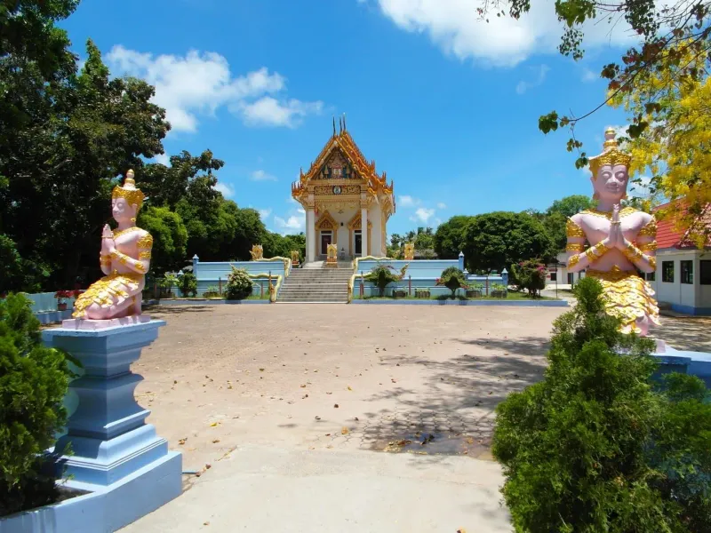 The entrance gate to Wat Khunaram with its sign and roadside shrine