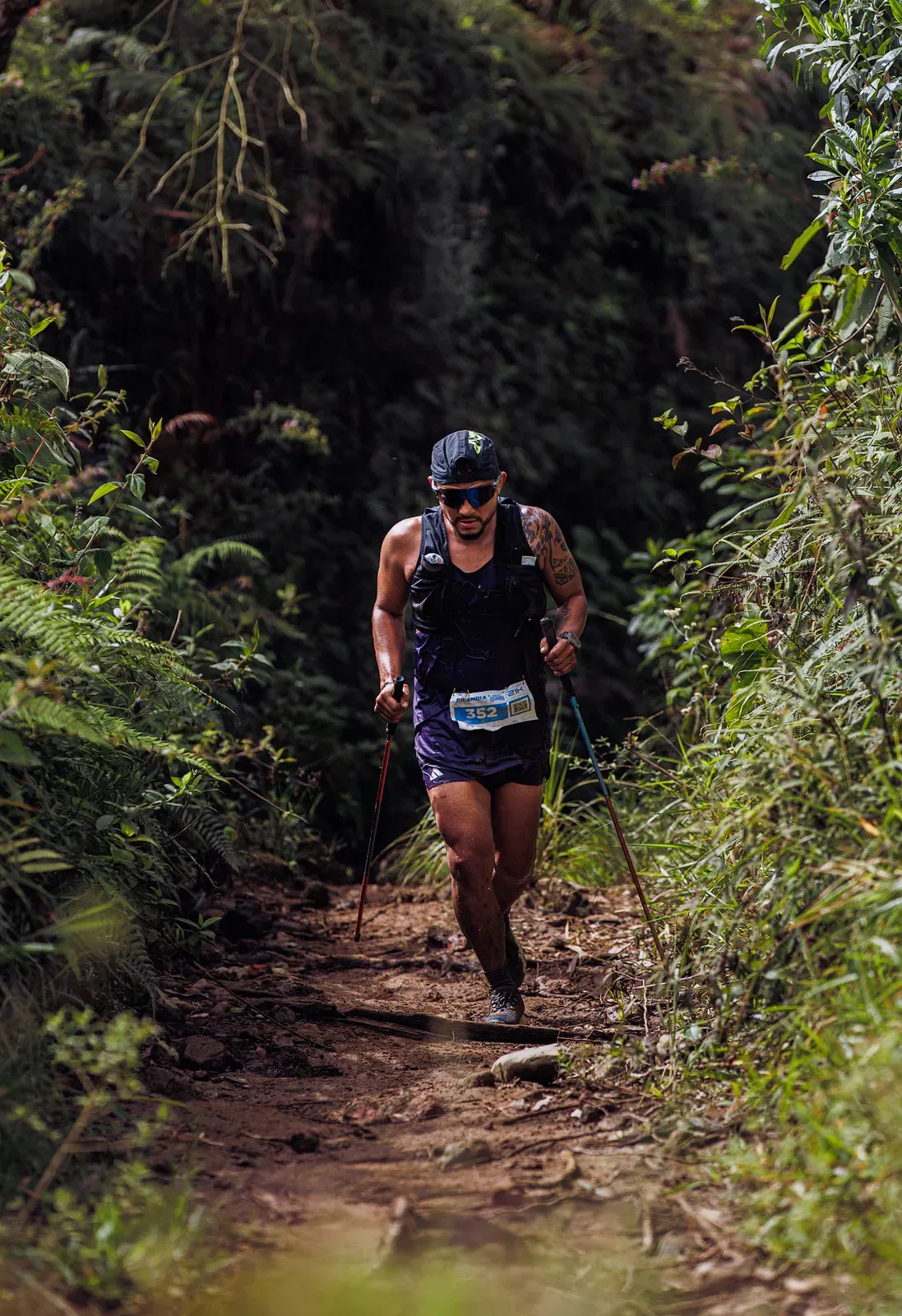 Trail runner with poles on a forest path