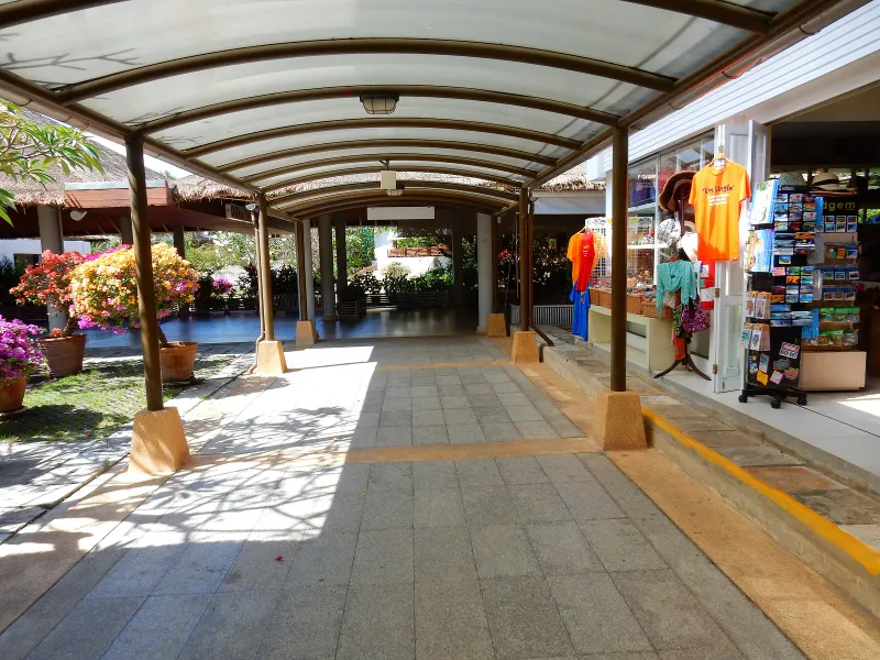Covered walkway lined with shops leading out of the Koh Samui Airport terminal toward the road