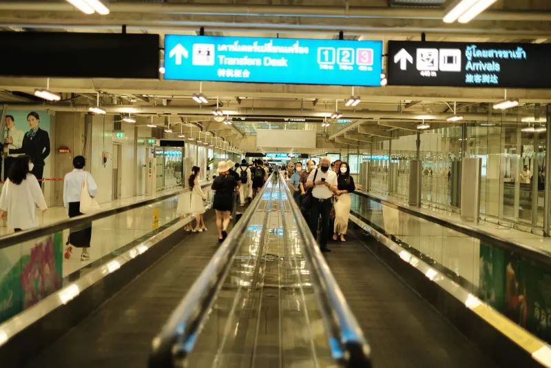 Passengers walking through the arrivals area at an airport before heading to a ride-hailing pickup point