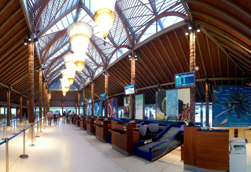 Open-air check-in hall with timber roof and departure screens at Koh Samui Airport