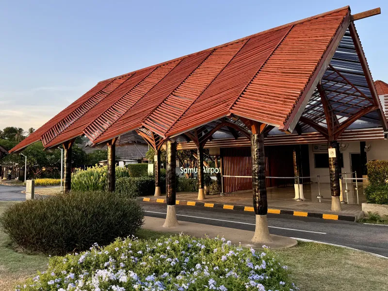 Samui Airport terminal building with a red tiled open roof and garden entrance
