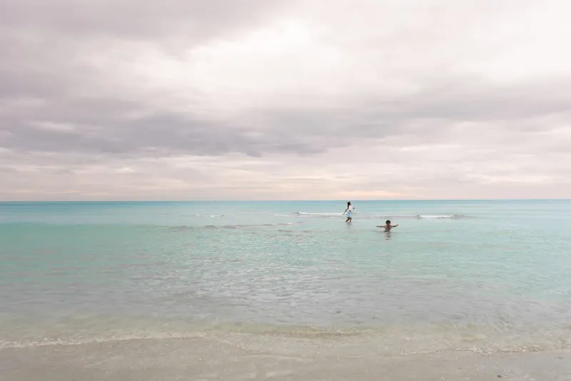 Children playing on a quiet beach under a cloudy sky, similar to Koh Samui's calmer coasts