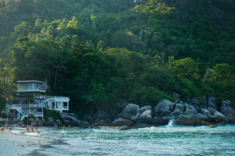 Tropical beach house surrounded by palm trees and green hills near Koh Samui's southeast coast