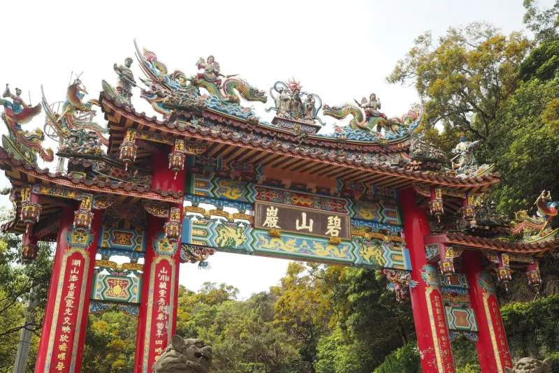 Vibrant Chinese temple gate with intricate dragon sculptures, the entrance style shared by Koh Samui's shrines
