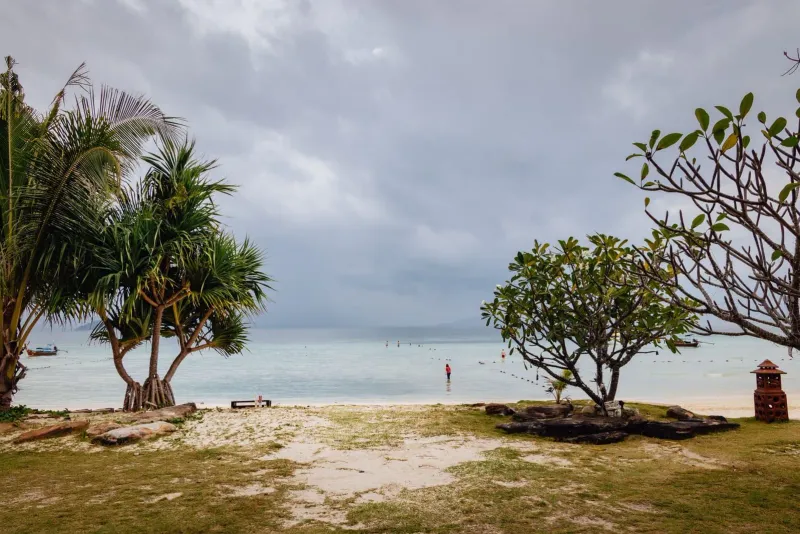 Cloudy sky over a quiet Thai beach with trees, similar to Koh Samui in October