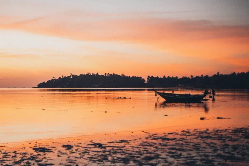 Silhouette of a longtail boat on calm water at sunset near Lipa Noi Pier on Koh Samui