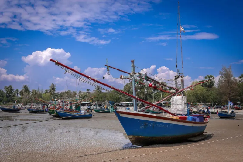 Traditional fishing boats resting on sand at low tide, similar to piers along Koh Samui's south coast