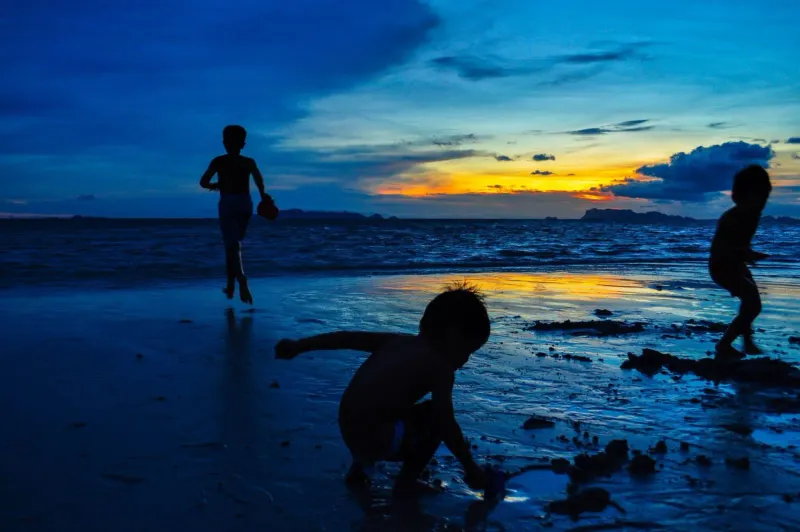 Silhouettes of children enjoying a free Koh Samui beach at sunset