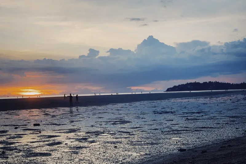 Visitors walking along a Koh Samui beach at sunset, a free evening activity