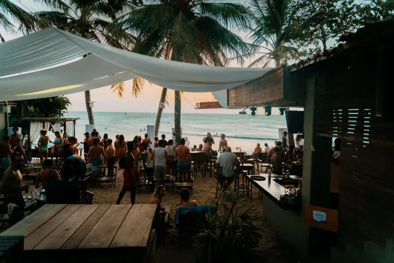 Lively beachside bar scene with people relaxing under palm trees at sunset in Chaweng Koh Samui