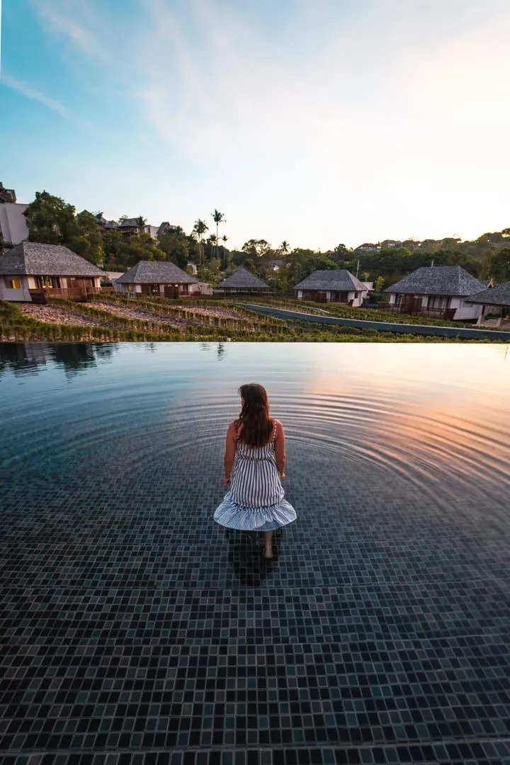 Guest standing in an infinity pool at sunset at a Koh Samui honeymoon resort