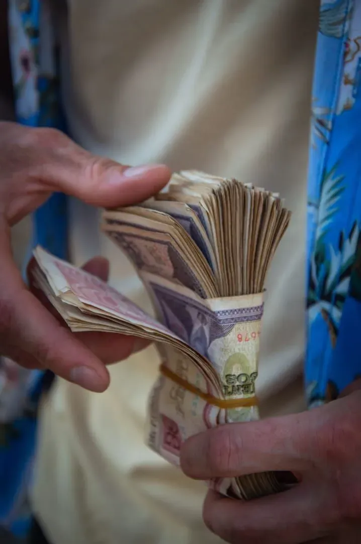 Hands counting Thai baht banknotes for a Koh Samui backpacker daily budget