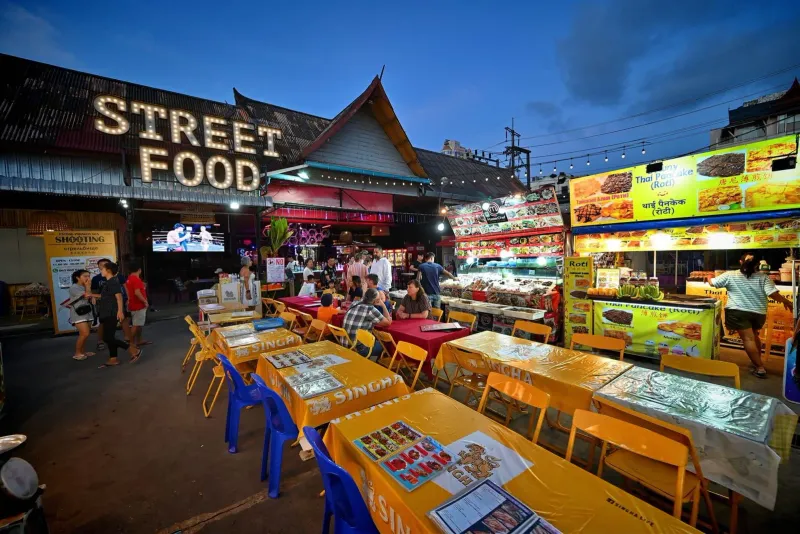 Colorful night market food stalls lit up after dark, the style of Maenam's Thursday market
