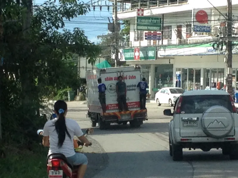 Mixed traffic of a scooter, a delivery truck and an SUV on a Koh Samui town street