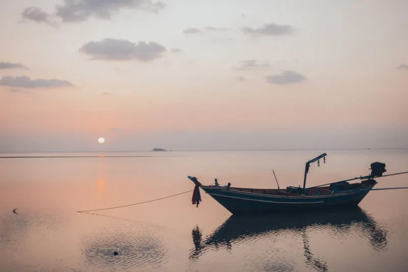 Lone boat silhouette on a tranquil sea during sunset near Lipa Noi Koh Samui