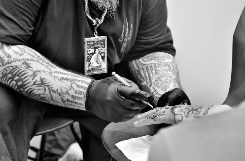 Tattoo artist's gloved hands guide a machine needle across a client's skin during a studio tattoo session