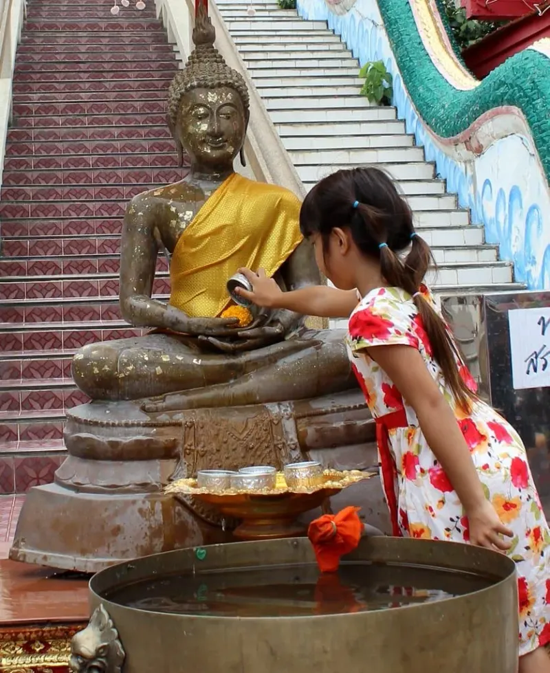 A girl placing an offering at a seated Buddha