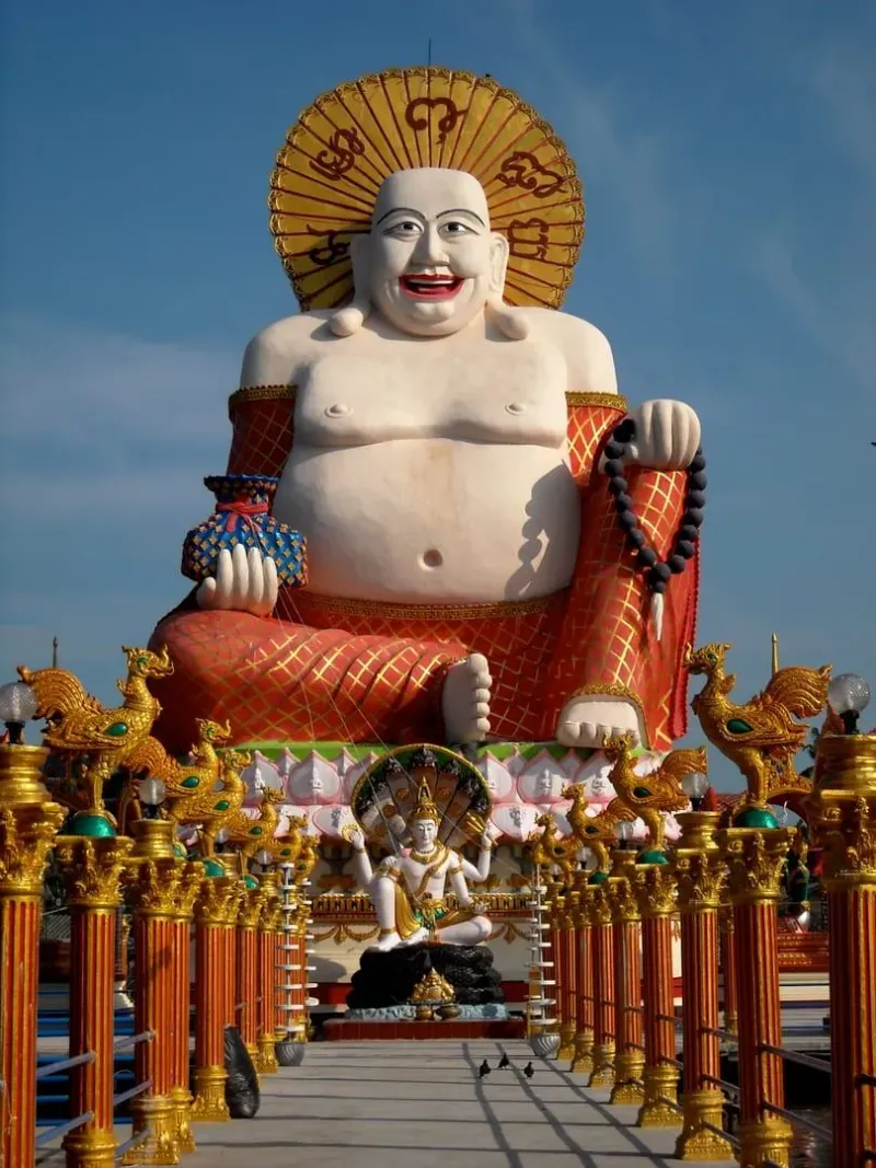 Buddha statue among the lakeside temple buildings of Wat Plai Laem near Bophut, Koh Samui, an example of a mixed Theravada and Mahayana site