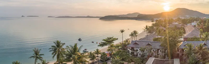 A bay at sunrise with palm trees and a beach on the north coast of Koh Samui