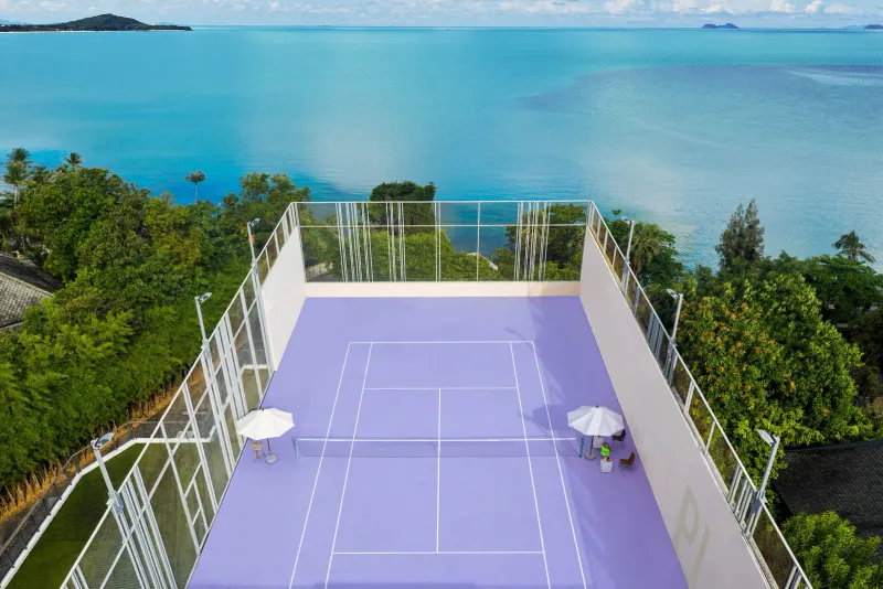 An aerial view of a purple hard court on a hilltop above the sea